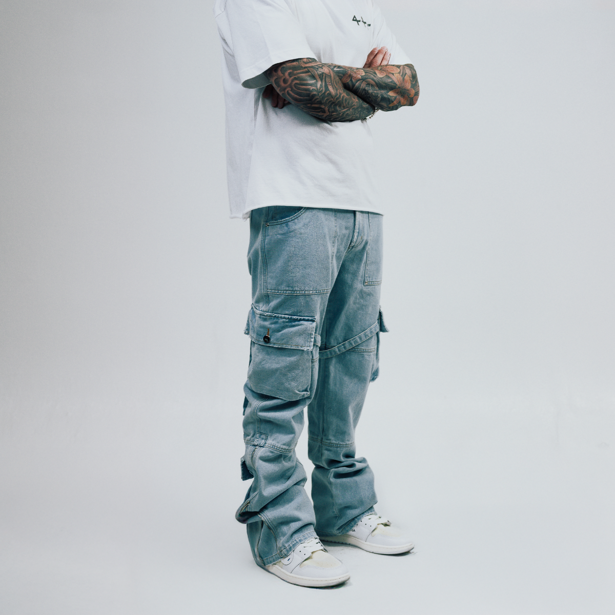 Person wearing light blue cargo pants and a white shirt on a plain background