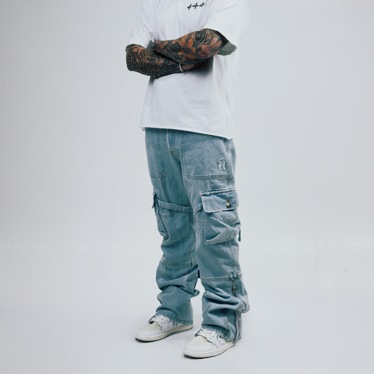 Person wearing a white sweatshirt, blue cargo pants, and white sneakers on a plain background