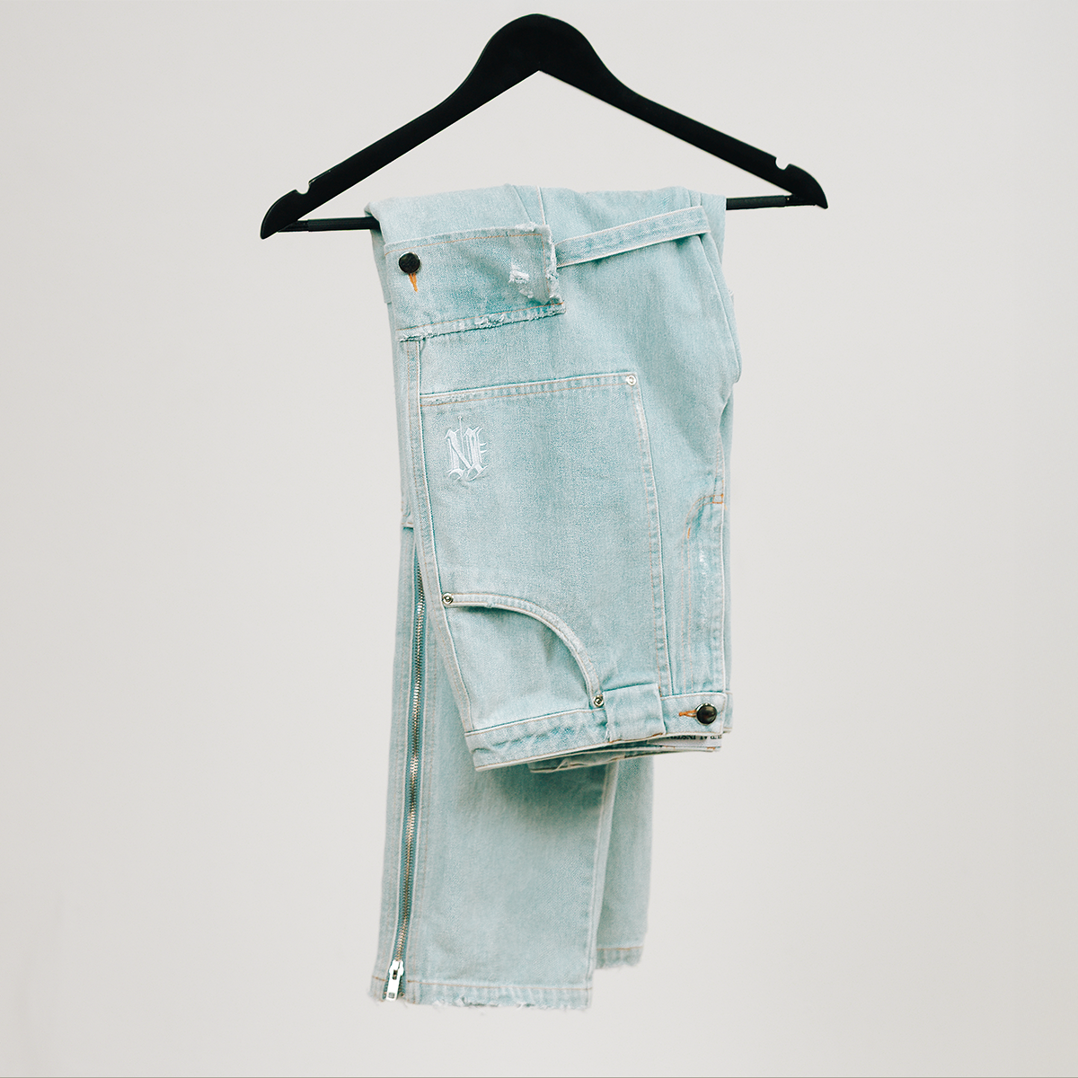 Light blue denim shorts on a black hanger against a light gray background