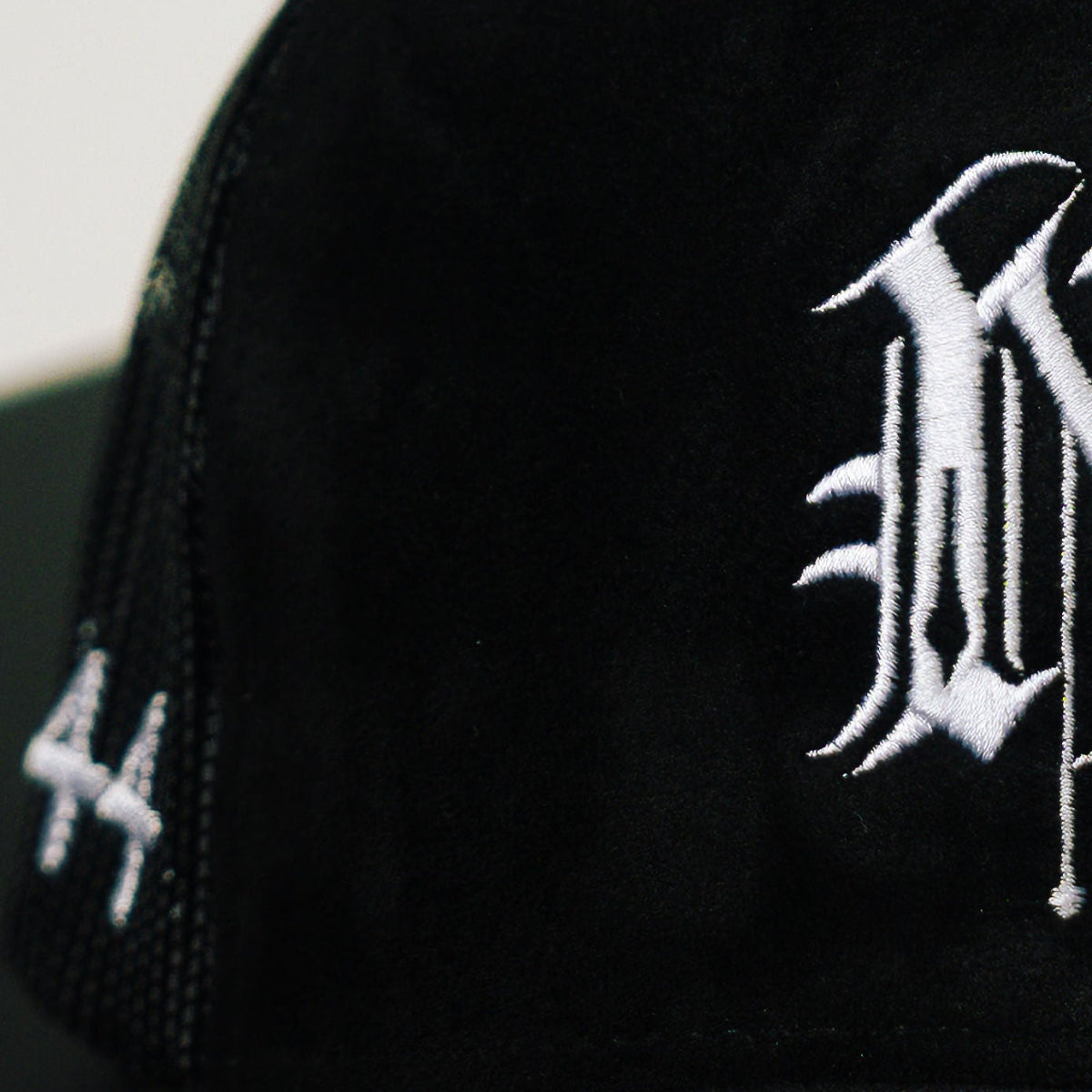 Black cap with white embroidered logo on a light gray background