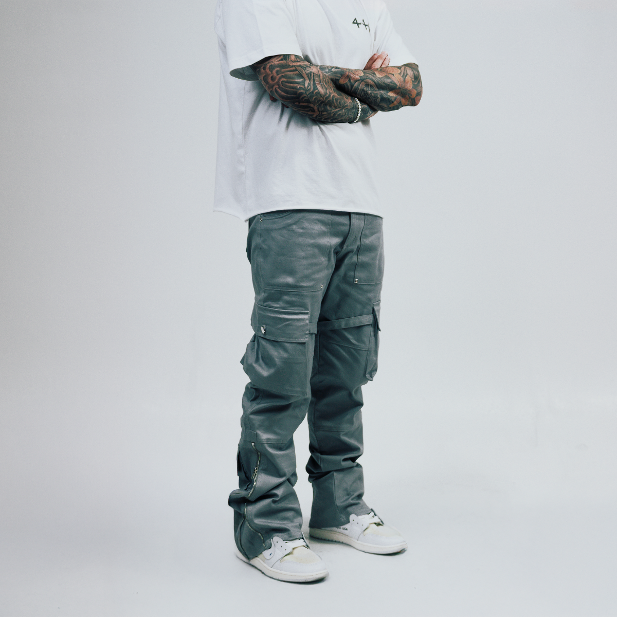 Person wearing dark cargo pants and a white shirt on a plain background